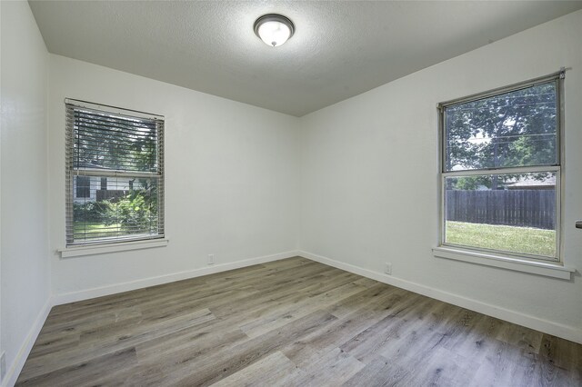 1601 Elizabeth Dr, Garland, TX 75042 - unfurnished room with wood finished floors, baseboards, and a textured ceiling