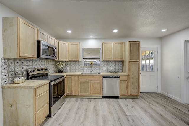 1601 Elizabeth Dr, Garland, TX 75042 - kitchen with appliances with stainless steel finishes, light brown cabinetry, a sink, light wood-type flooring, and backsplash