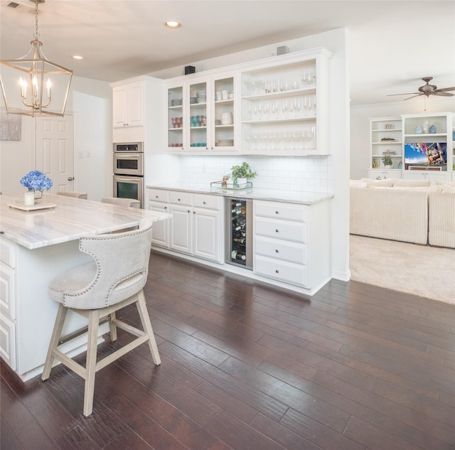 7002 Clear Springs Pkwy, Garland, TX 75044 - kitchen with stainless steel double oven, beverage cooler, white cabinetry, light stone countertops, and recessed lighting