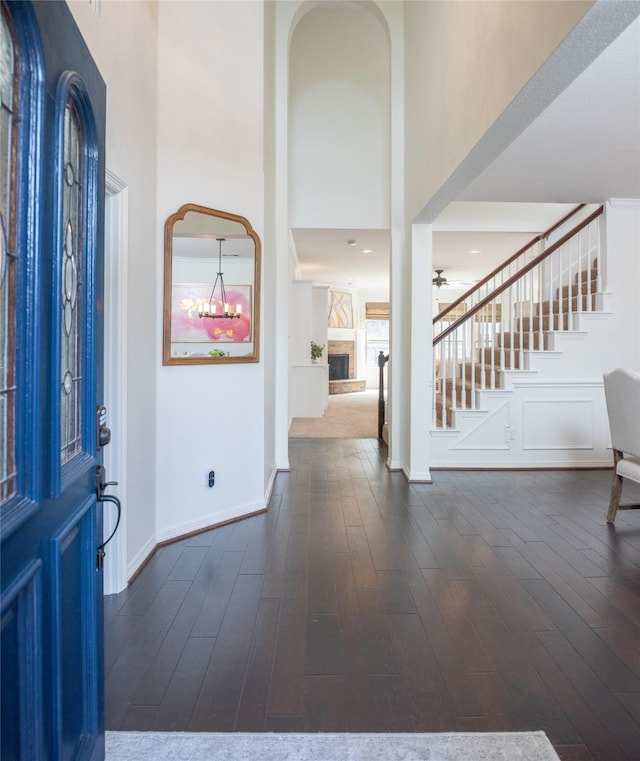 7002 Clear Springs Pkwy, Garland, TX 75044 - foyer featuring a towering ceiling, stairway, a fireplace with raised hearth, baseboards, and dark wood-type flooring