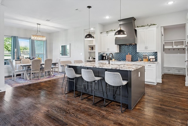 1025 Aledo Ridge Ct, Fort Worth, TX 76108 - kitchen featuring a center island with sink, light stone countertops, backsplash, a kitchen breakfast bar, and white cabinetry