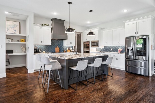 1025 Aledo Ridge Ct, Fort Worth, TX 76108 - kitchen with appliances with stainless steel finishes, wall chimney range hood, an island with sink, dark wood finished floors, and recessed lighting