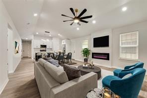 1320 E 3rd Ave, Corsicana, TX 75110 - living area featuring vaulted ceiling, a glass covered fireplace, baseboards, wood finished floors, and recessed lighting