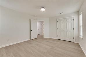 1320 E 3rd Ave, Corsicana, TX 75110 - unfurnished bedroom featuring baseboards, light wood-style floors, and a closet