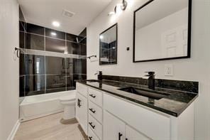 1320 E 3rd Ave, Corsicana, TX 75110 - bathroom featuring toilet, double vanity, combined bath / shower with glass door, wood finished floors, and baseboards