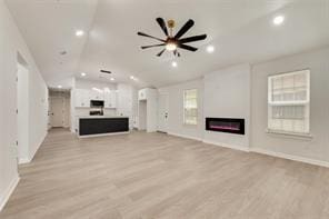 1320 E 3rd Ave, Corsicana, TX 75110 - unfurnished living room featuring lofted ceiling, a glass covered fireplace, light wood-type flooring, baseboards, and recessed lighting