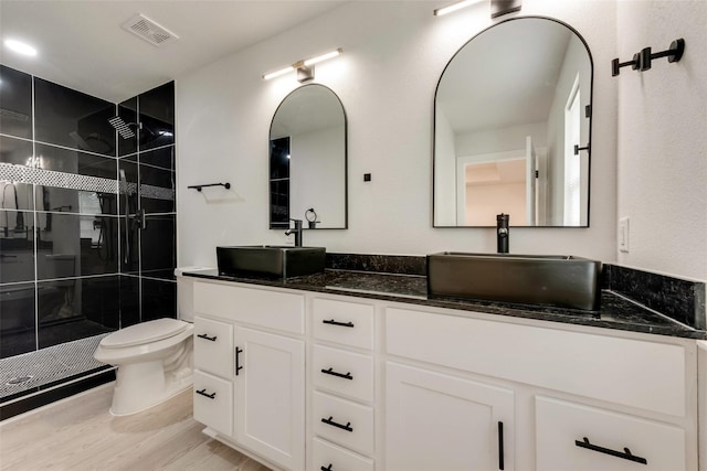 1320 E 3rd Ave, Corsicana, TX 75110 - bathroom featuring double vanity, a shower stall, toilet, and wood finished floors