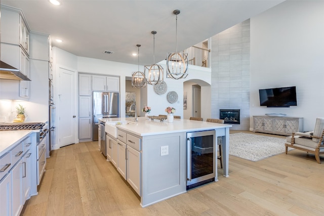 3525 Dancer Rd, Celina, TX 75009 - kitchen with beverage cooler, light wood finished floors, a chandelier, arched walkways, and appliances with stainless steel finishes