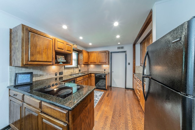 408 Davis St, Weatherford, TX 76086 - kitchen featuring black appliances, brown cabinets, tasteful backsplash, wood finished floors, and a peninsula