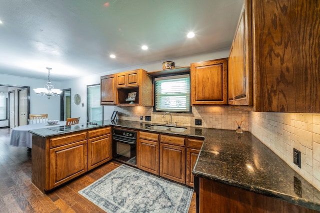 408 Davis St, Weatherford, TX 76086 - kitchen featuring black appliances, a peninsula, dark wood finished floors, a chandelier, and brown cabinets