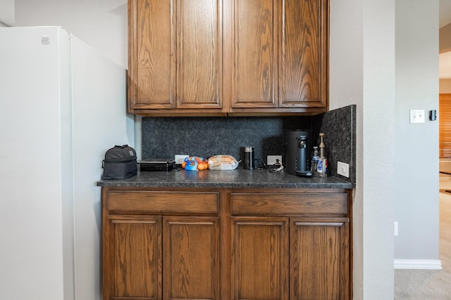 7807 Enchanted Isle Dr, Arlington, TX 76016 - kitchen featuring dark countertops, brown cabinets, tasteful backsplash, and freestanding refrigerator