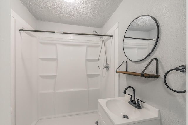 408 E Baylor St, Weatherford, TX 76086 - bathroom featuring a textured ceiling, a shower, a textured wall, and vanity
