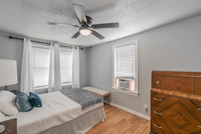 408 E Baylor St, Weatherford, TX 76086 - bedroom with light wood-style flooring, cooling unit, a textured ceiling, a ceiling fan, and baseboards