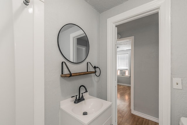 408 E Baylor St, Weatherford, TX 76086 - bathroom featuring a textured ceiling, wood finished floors, vanity, and baseboards