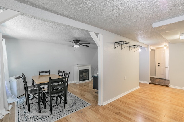 408 E Baylor St, Weatherford, TX 76086 - dining area with a ceiling fan, a glass covered fireplace, light wood finished floors, a textured ceiling, and baseboards