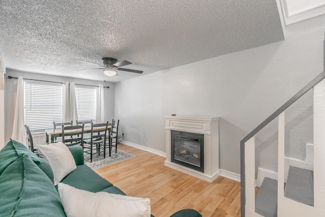 408 E Baylor St, Weatherford, TX 76086 - living area featuring light wood finished floors, ceiling fan, a textured ceiling, a glass covered fireplace, and baseboards