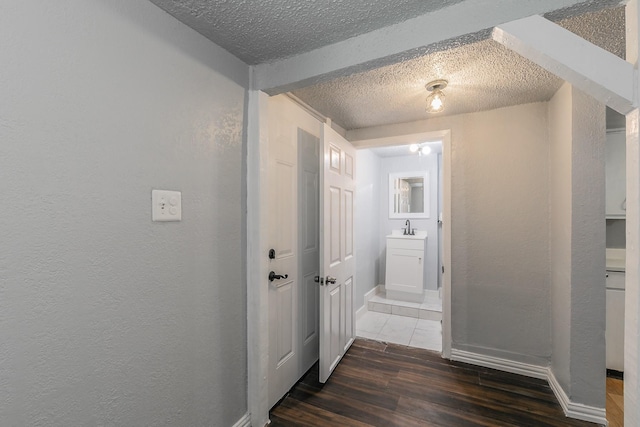 408 E Baylor St, Weatherford, TX 76086 - hall featuring a textured ceiling, wood finished floors, a sink, a textured wall, and baseboards
