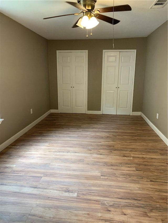 302 W Dexter St, Sherman, TX 75092 - unfurnished bedroom featuring baseboards, wood finished floors, a ceiling fan, and multiple closets