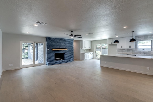 10240 Carry Back Cir, Dallas, TX 75229 - unfurnished living room featuring a textured ceiling, a sink, a ceiling fan, recessed lighting, and a brick fireplace