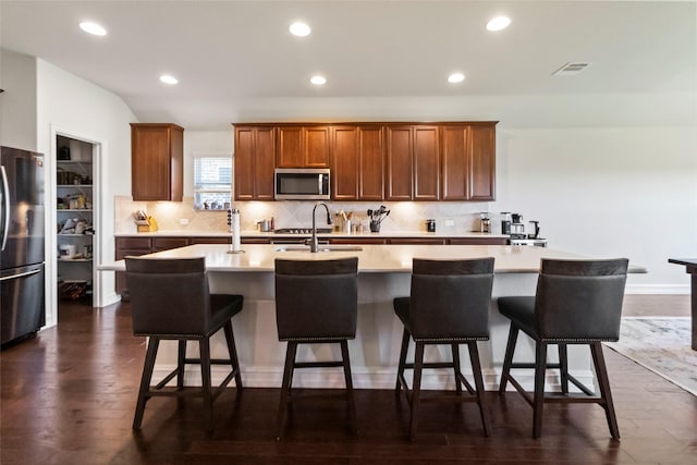 1424 Millican Ln, Aubrey, TX 76227 - kitchen featuring appliances with stainless steel finishes, tasteful backsplash, light countertops, a sink, and a center island with sink
