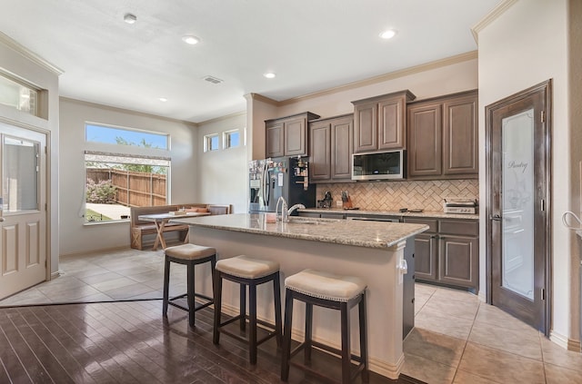 3113 Sangria Ln, Fort Worth, TX 76177 - kitchen with appliances with stainless steel finishes, ornamental molding, a kitchen bar, a kitchen island with sink, and tasteful backsplash