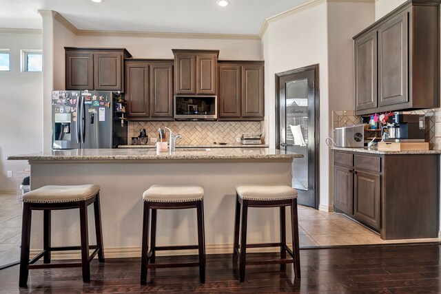 3113 Sangria Ln, Fort Worth, TX 76177 - kitchen with appliances with stainless steel finishes, dark brown cabinets, crown molding, decorative backsplash, and an island with sink