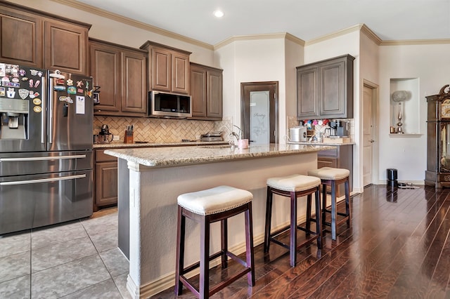 3113 Sangria Ln, Fort Worth, TX 76177 - kitchen featuring stainless steel appliances, a breakfast bar area, light stone countertops, tasteful backsplash, and ornamental molding