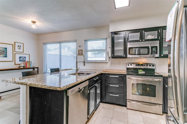 4223 Wild Plum Dr, Carrollton, TX 75010 - kitchen featuring appliances with stainless steel finishes, a sink, light tile patterned floors, dark cabinetry, and a textured ceiling