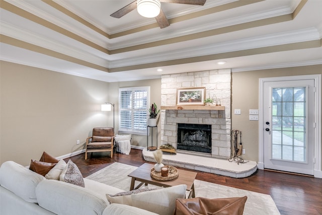 13914 Overlook Ln, Forney, TX 75126 - living room featuring crown molding, dark wood finished floors, a raised ceiling, ceiling fan, and a stone fireplace