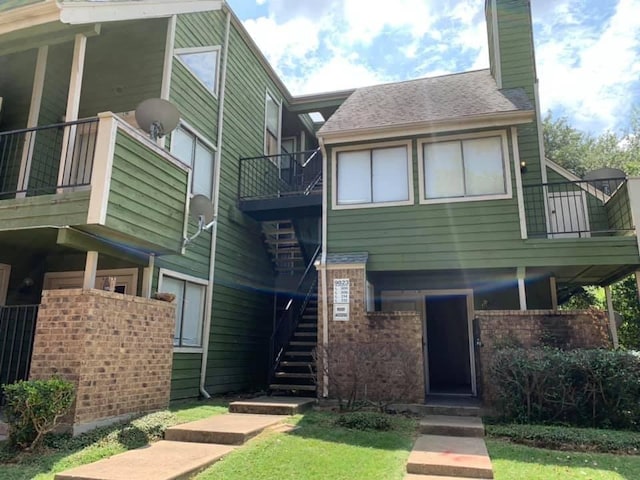 9823 Walnut St Unit L112, Dallas, TX 75243 - view of front facade featuring a balcony, a chimney, brick siding, stairway, and a front lawn