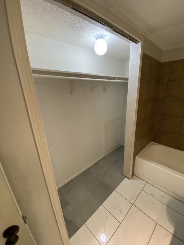 9823 Walnut St Unit L112, Dallas, TX 75243 - bathroom featuring a walk in closet and a textured ceiling