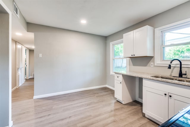 6632 Avalon Dr, Watauga, TX 76148 - kitchen featuring a sink, light stone counters, white cabinets, light wood-style floors, and plenty of natural light