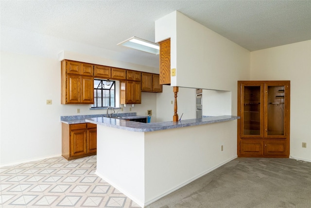 4007 Cherokee Ct, Granbury, TX 76048 - kitchen with brown cabinetry, a peninsula, a textured ceiling, and baseboards