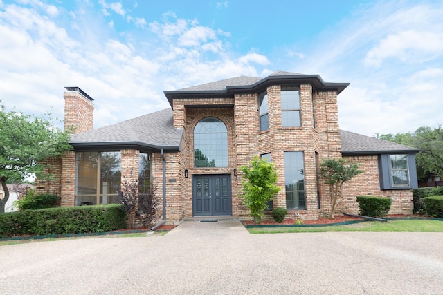 2302 Tiffany Ct, Garland, TX 75043 - traditional-style home featuring a shingled roof, brick siding, and a chimney