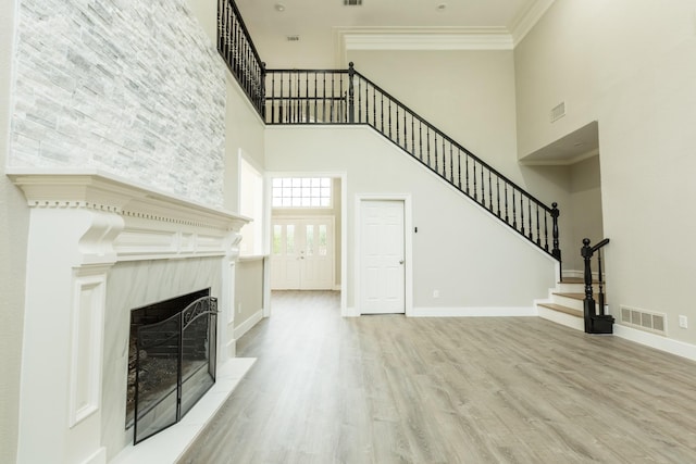2302 Tiffany Ct, Garland, TX 75043 - unfurnished living room with a towering ceiling, stairs, a fireplace, wood finished floors, and crown molding