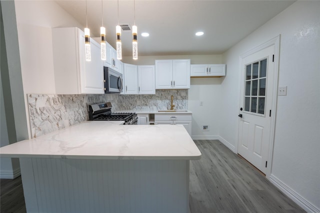 1620 E King St, Sherman, TX 75090 - kitchen with appliances with stainless steel finishes, wood finished floors, a peninsula, backsplash, and white cabinetry