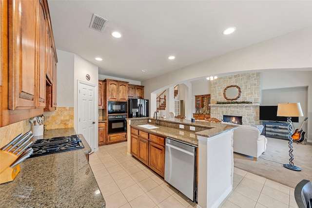 15534 Fox Meadow Ln, Frisco, TX 75035 - kitchen featuring black appliances, arched walkways, light tile patterned floors, a sink, and a fireplace