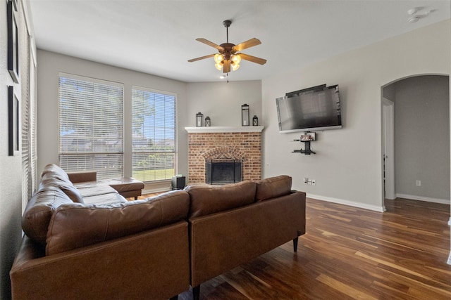 7008 Clipper Dr, Grand Prairie, TX 75054 - living room featuring a fireplace, dark wood-style floors, arched walkways, baseboards, and a ceiling fan