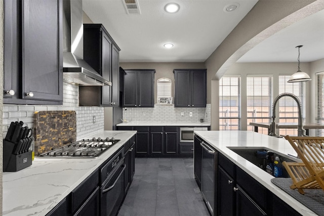 7008 Clipper Dr, Grand Prairie, TX 75054 - kitchen featuring wall chimney range hood, stainless steel appliances, dark cabinets, a sink, and arched walkways