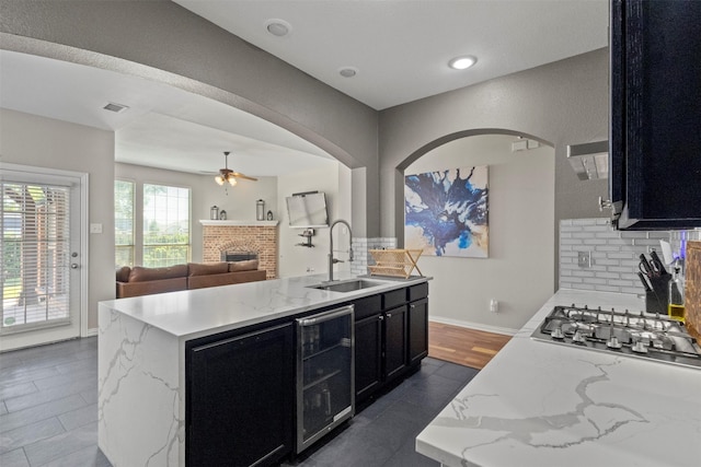 7008 Clipper Dr, Grand Prairie, TX 75054 - kitchen with a sink, dark cabinetry, beverage cooler, stainless steel gas stovetop, and ceiling fan
