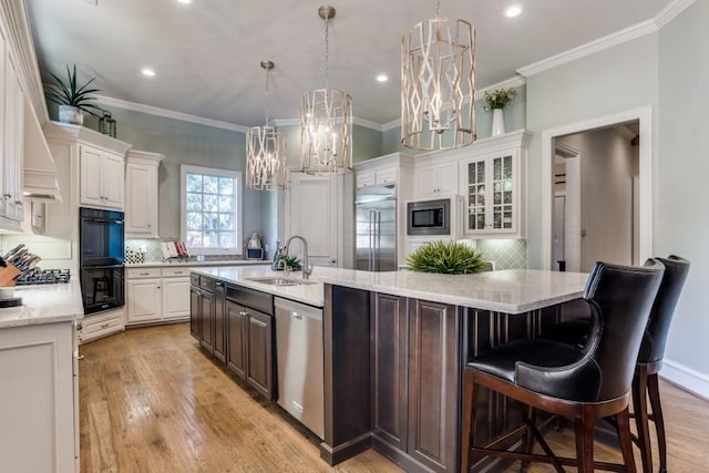 2709 Redding Dr, Plano, TX 75093 - kitchen featuring a sink, built in appliances, a kitchen island with sink, white cabinets, and ornamental molding