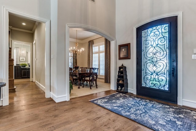 2709 Redding Dr, Plano, TX 75093 - entryway featuring a chandelier, wood finished floors, crown molding, baseboards, and arched walkways
