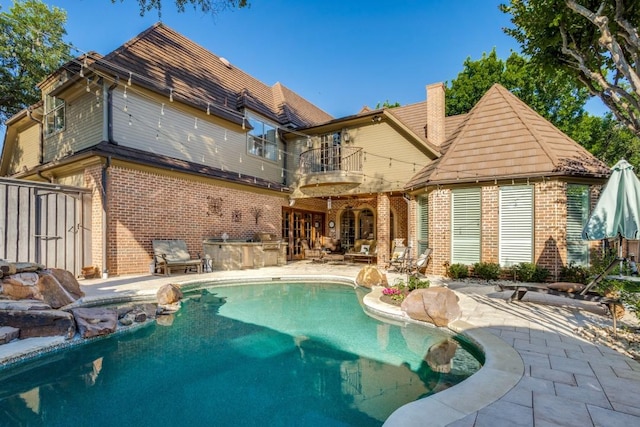 2709 Redding Dr, Plano, TX 75093 - back of property featuring a balcony, brick siding, a patio area, an outdoor kitchen, and an outdoor pool