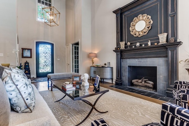 2709 Redding Dr, Plano, TX 75093 - living area with wood finished floors, a tile fireplace, a high ceiling, and a chandelier