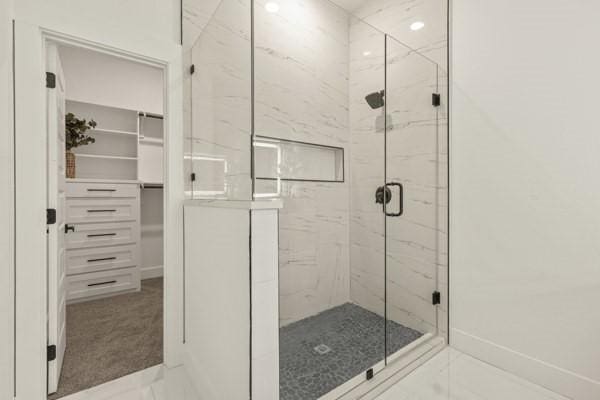 301 Bay Ct, Gun Barrel City, TX 75156 - bathroom featuring a marble finish shower, a walk in closet, marble finish flooring, and baseboards