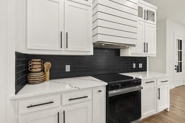 301 Bay Ct, Gun Barrel City, TX 75156 - kitchen with electric stove, white cabinets, custom range hood, and light wood finished floors