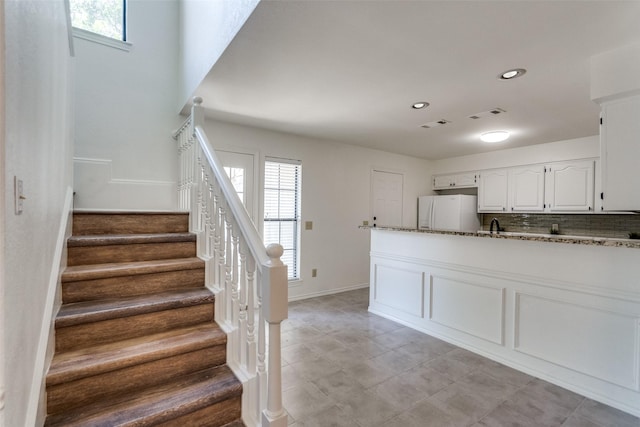 3631 Hilltop Ln, Plano, TX 75023 - kitchen featuring freestanding refrigerator, dark stone counters, white cabinets, healthy amount of natural light, and recessed lighting