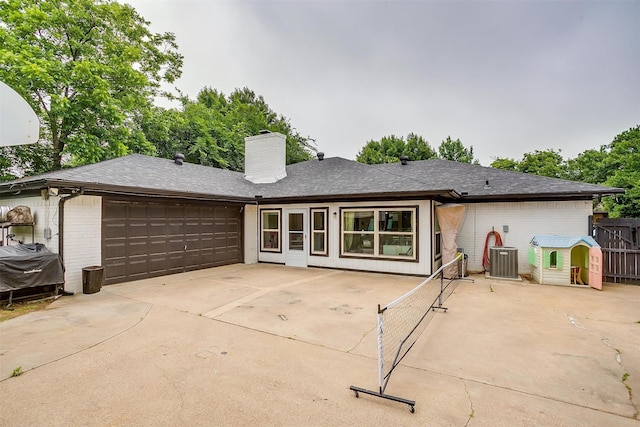 217 NE Rosamond St, Burleson, TX 76028 - back of house with brick siding, a chimney, a garage, driveway, and central AC unit