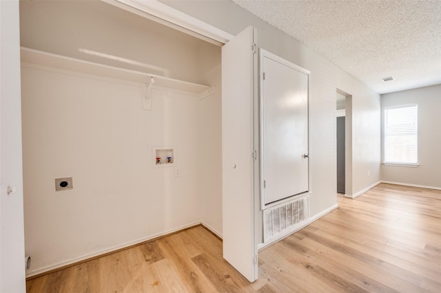 2521 Markland St, Irving, TX 75060 - laundry room featuring electric dryer hookup, washer hookup, a textured ceiling, light wood-style flooring, and baseboards