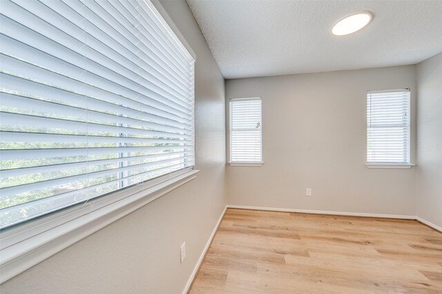 2521 Markland St, Irving, TX 75060 - unfurnished room with healthy amount of natural light, light wood-style flooring, baseboards, and a textured ceiling